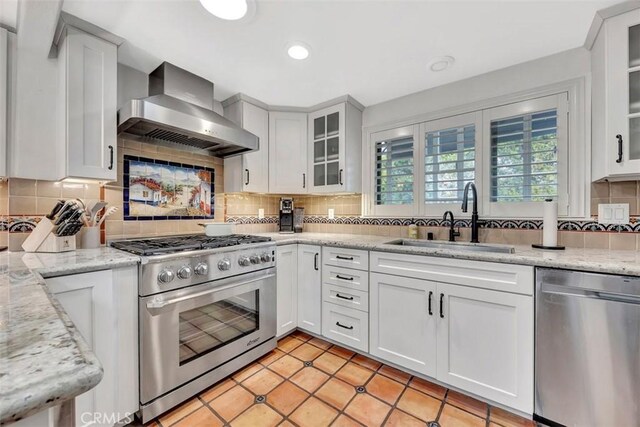 306 Avenida Monterey, San Clemente, CA 92672 - kitchen with stainless steel appliances, wall chimney range hood, a sink, decorative backsplash, and white cabinetry