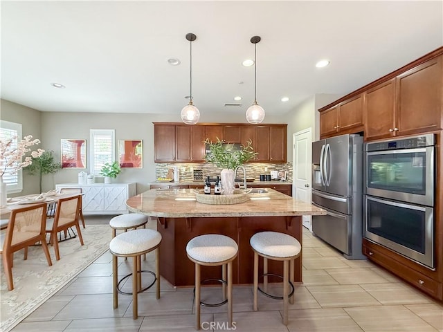 6184 Lafayette St, Chino, CA 91710 - kitchen featuring appliances with stainless steel finishes, decorative backsplash, a breakfast bar area, a sink, and light stone countertops