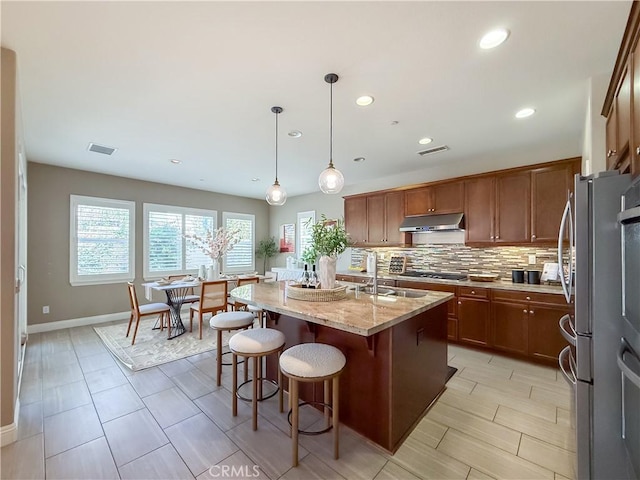 6184 Lafayette St, Chino, CA 91710 - kitchen featuring under cabinet range hood, freestanding refrigerator, a sink, light stone countertops, and baseboards