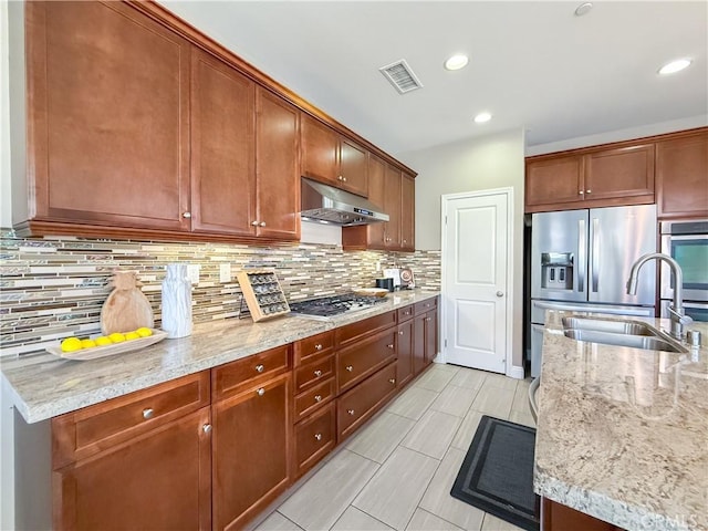 6184 Lafayette St, Chino, CA 91710 - kitchen with under cabinet range hood, a sink, appliances with stainless steel finishes, tasteful backsplash, and light stone countertops