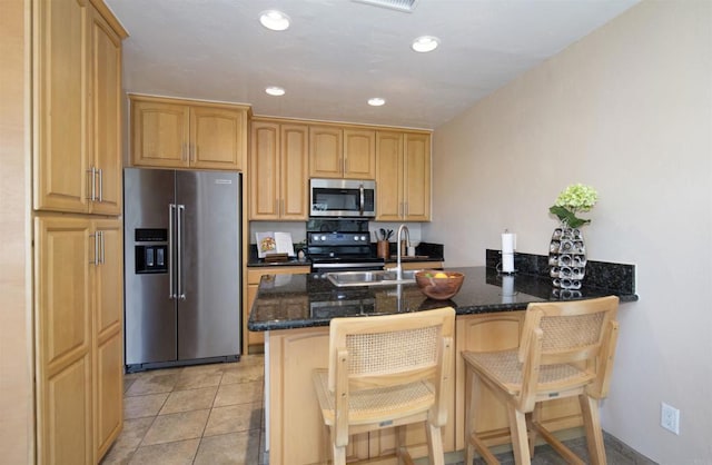 3625 Vista Oceana Unit 18, Oceanside, CA 92057 - kitchen with stainless steel appliances, a sink, dark stone countertops, a peninsula, and a kitchen bar