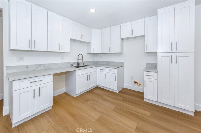 22016 Schoolcraft St, Canoga Park, CA 91303 - kitchen featuring a sink, baseboards, light wood finished floors, white cabinetry, and light stone counters