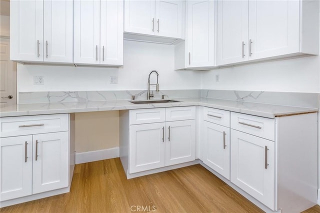 22016 Schoolcraft St, Canoga Park, CA 91303 - kitchen with a sink, light wood finished floors, white cabinets, and light stone counters