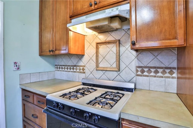 1706 James Pl, Pomona, CA 91767 - kitchen with white gas stove, under cabinet range hood, light countertops, and tasteful backsplash