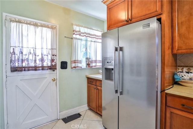 1706 James Pl, Pomona, CA 91767 - kitchen featuring stainless steel fridge, brown cabinetry, light countertops, light tile patterned floors, and baseboards