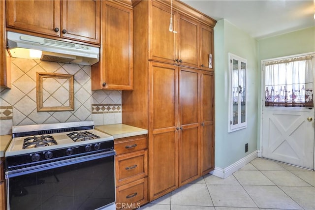 1706 James Pl, Pomona, CA 91767 - kitchen with gas range oven, under cabinet range hood, light tile patterned floors, brown cabinets, and light countertops