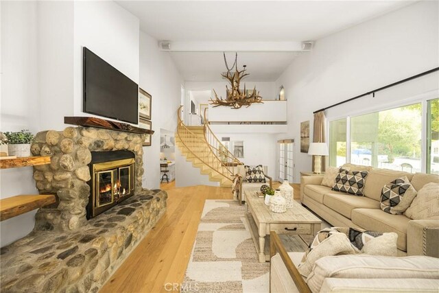 29422 Modjeska Canyon Rd, Modjeska Canyon, CA 92676 - living room with wood finished floors, a stone fireplace, beam ceiling, stairs, and a chandelier