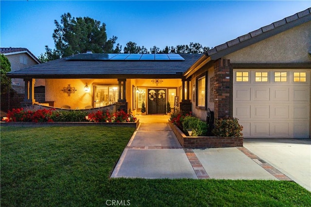 42311 Camden Way, Lancaster, CA 93536 - view of front of home with roof mounted solar panels, a front lawn, a garage, stone siding, and covered porch