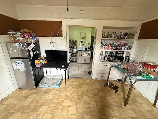 415417 Euclid Ave, Los Angeles, CA 90063 - kitchen featuring freestanding refrigerator, a decorative wall, wainscoting, and white cabinetry