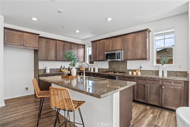 16725 Petrus Ln, Fontana, CA 92336 - kitchen with appliances with stainless steel finishes, a sink, wood finished floors, dark stone countertops, and recessed lighting