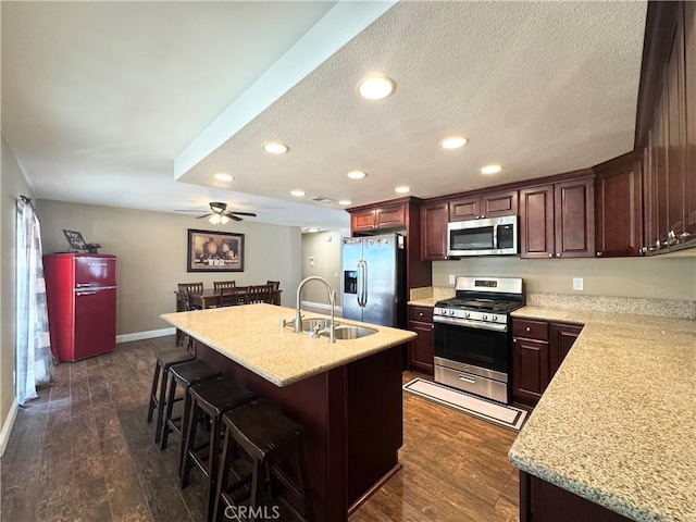 7425 I Ave, Hesperia, CA 92345 - kitchen featuring appliances with stainless steel finishes, a sink, a ceiling fan, a breakfast bar area, and dark wood-style flooring