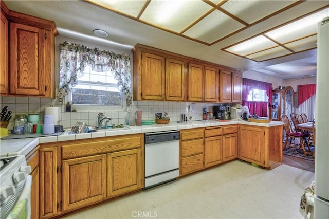 9419 Bartley Ave, Santa Fe Springs, CA 90670 - kitchen with white dishwasher, light flooring, brown cabinetry, tasteful backsplash, and a peninsula