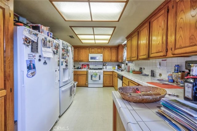9419 Bartley Ave, Santa Fe Springs, CA 90670 - kitchen with white appliances, tile countertops, brown cabinets, backsplash, and light flooring