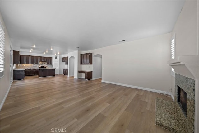 8840 Greenlawn St, Riverside, CA 92508 - unfurnished living room with arched walkways, a fireplace with flush hearth, light wood-type flooring, and baseboards