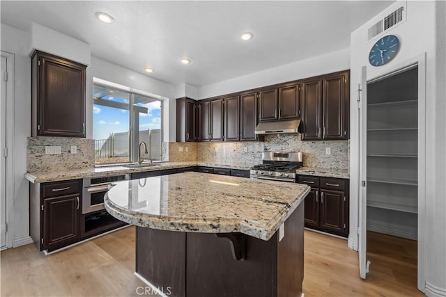 8840 Greenlawn St, Riverside, CA 92508 - kitchen with appliances with stainless steel finishes, under cabinet range hood, light wood-style floors, decorative backsplash, and a center island