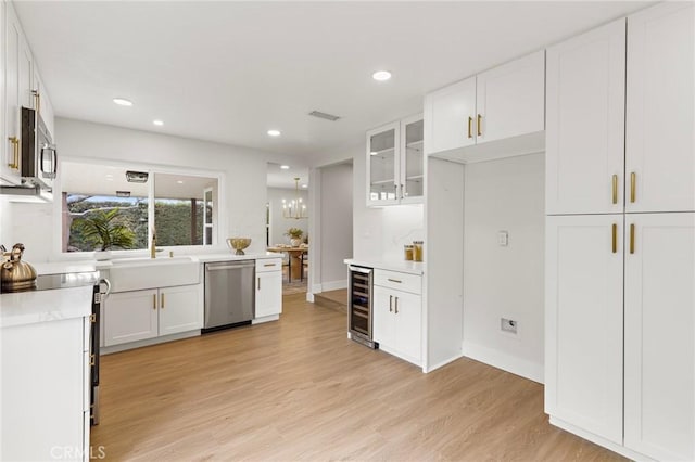 7848 Calmcrest Dr, Downey, CA 90240 - kitchen featuring appliances with stainless steel finishes, white cabinetry, beverage cooler, light wood-type flooring, and recessed lighting