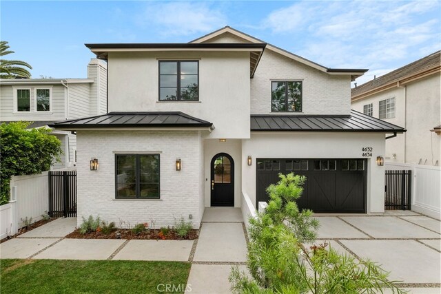 4634 Vesper Ave, Sherman Oaks, CA 91403 - view of front of home with a standing seam roof, driveway, an attached garage, brick siding, and a metal roof