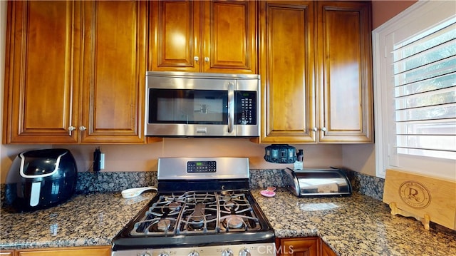14862 Temple Ave, La Puente, CA 91744 - kitchen with appliances with stainless steel finishes, dark stone countertops, and brown cabinetry
