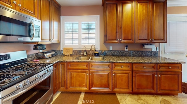 14862 Temple Ave, La Puente, CA 91744 - kitchen with appliances with stainless steel finishes, a sink, dark stone counters, light tile patterned floors, and brown cabinetry