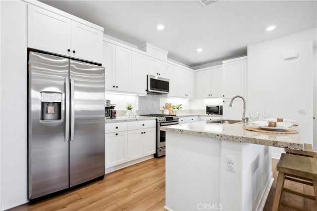 1101 Lasso Way Unit 303, Rancho Mission Viejo, CA 92694 - kitchen featuring stainless steel appliances, a sink, white cabinetry, light wood-type flooring, and light stone countertops