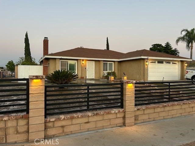 321 N Brampton Ave, Rialto, CA 92376 - view of front facade with a garage, a fenced front yard, and a chimney