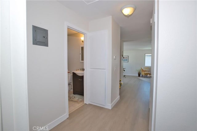 16387 De Anza Cir Unit Ci60, Huntington Beach, CA 92649 - corridor featuring electric panel, light wood-style flooring, a sink, and baseboards