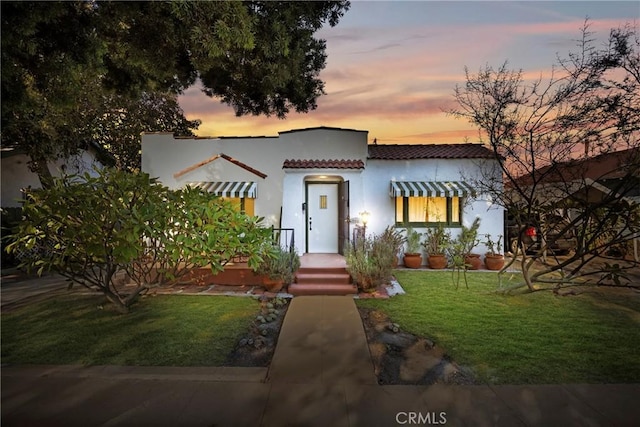 225 E 56th St, Long Beach, CA 90805 - mediterranean / spanish house with a tile roof, a lawn, and stucco siding