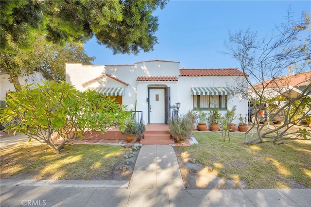 225 E 56th St, Long Beach, CA 90805 - mediterranean / spanish home featuring a tiled roof, stucco siding, and a front lawn
