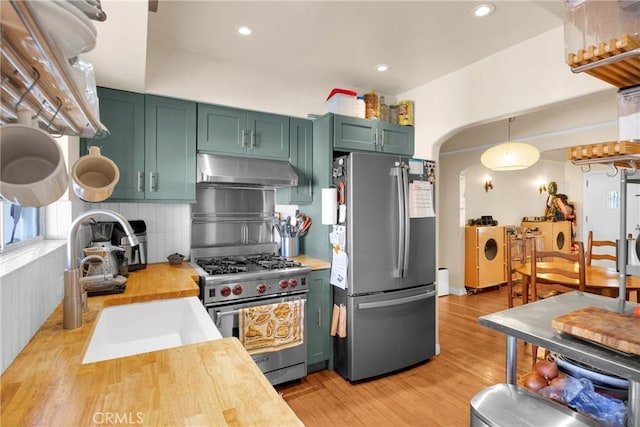 225 E 56th St, Long Beach, CA 90805 - kitchen with appliances with stainless steel finishes, under cabinet range hood, green cabinetry, wood counters, and arched walkways