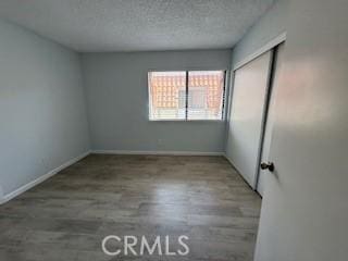 2208 N N Broadway Unit 33, Santa Ana, CA 92706 - unfurnished bedroom with wood finished floors, a textured ceiling, a closet, and baseboards