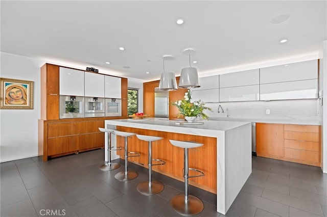 1088 Del Mar Ave, Laguna Beach, CA 92651 - kitchen with modern cabinets, a center island, light countertops, brown cabinets, and recessed lighting