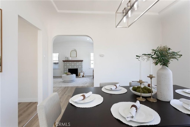 1116 W 80th St, Los Angeles, CA 90044 - dining room featuring arched walkways, wood finished floors, and a tile fireplace