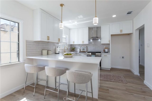 1116 W 80th St, Los Angeles, CA 90044 - kitchen with wall chimney exhaust hood, white cabinetry, tasteful backsplash, a peninsula, and recessed lighting