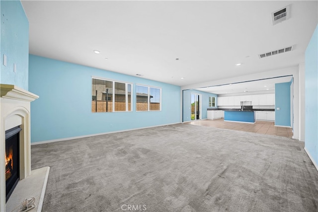 11877 Crossbill Way, Jurupa Valley, CA 91752 - unfurnished living room featuring a lit fireplace, light carpet, recessed lighting, and baseboards