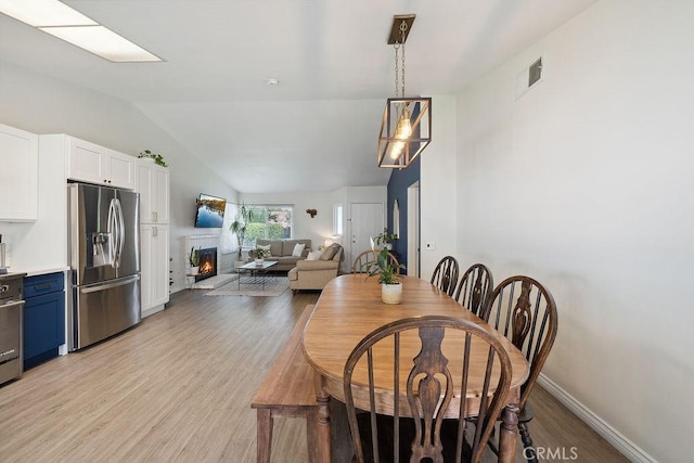 27721 Wakefield Rd, Castaic, CA 91384 - dining space featuring lofted ceiling, light wood finished floors, a lit fireplace, and baseboards