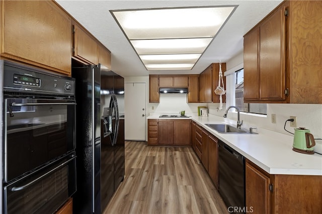 819 Shade Tree Ln, Fallbrook, CA 92028 - kitchen with black appliances, a sink, light wood-style floors, brown cabinetry, and a warming drawer