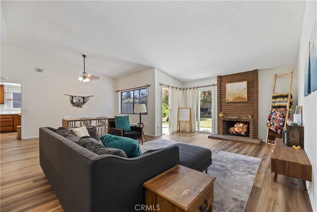 819 Shade Tree Ln, Fallbrook, CA 92028 - living room with a textured ceiling, lofted ceiling, ceiling fan, a fireplace, and light wood-style flooring