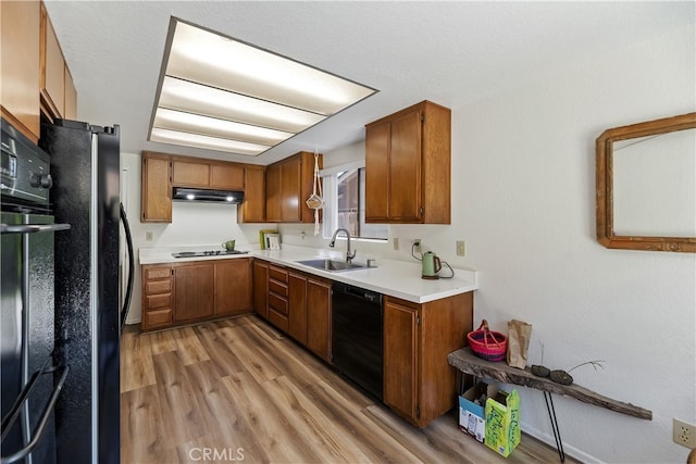 819 Shade Tree Ln, Fallbrook, CA 92028 - kitchen with black appliances, a sink, under cabinet range hood, brown cabinetry, and light wood-style flooring