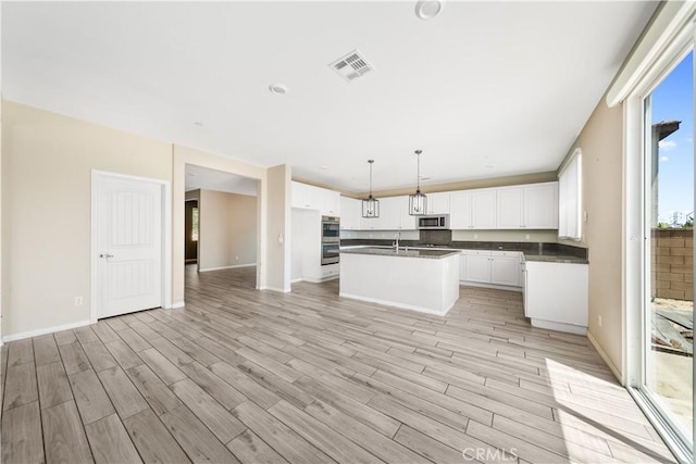 11836 Crossbill Way, Jurupa Valley, CA 91752 - kitchen featuring stainless steel appliances, dark countertops, light wood finished floors, and white cabinetry