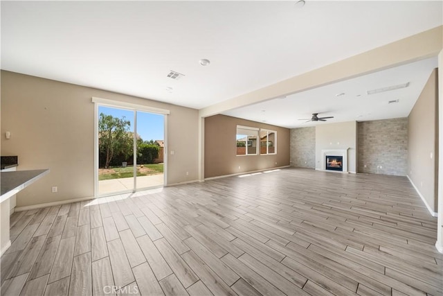 11836 Crossbill Way, Jurupa Valley, CA 91752 - unfurnished living room featuring light wood finished floors, baseboards, a lit fireplace, and ceiling fan