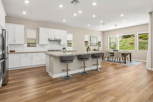675 Westbrook Loop, San Marcos, CA 92078 - kitchen featuring under cabinet range hood, plenty of natural light, a breakfast bar area, white cabinets, and recessed lighting