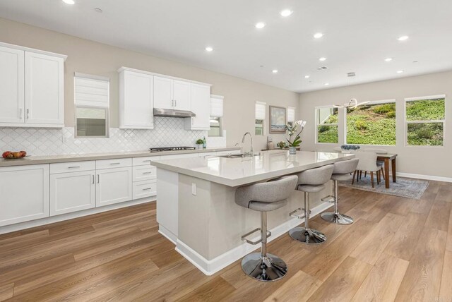 675 Westbrook Loop, San Marcos, CA 92078 - kitchen with gas cooktop, light wood-style floors, a sink, a breakfast bar area, and under cabinet range hood