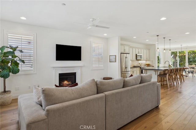 3207 Daisy Ln, San Luis Obispo, CA 93401 - living area with light wood-style flooring, a glass covered fireplace, recessed lighting, ceiling fan, and baseboards