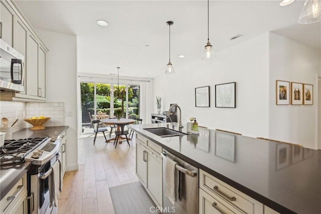 3207 Daisy Ln, San Luis Obispo, CA 93401 - kitchen featuring appliances with stainless steel finishes, a sink, dark countertops, light wood-style floors, and recessed lighting