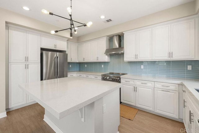 1105 Hibiscus Way, Oceanside, CA 92054 - kitchen with appliances with stainless steel finishes, wall chimney exhaust hood, a chandelier, white cabinets, and light countertops