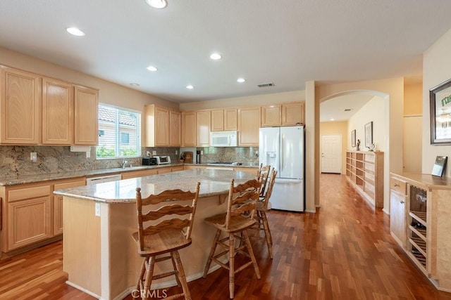 29557 Warmsprings Dr, Menifee, CA 92584 - kitchen featuring white appliances, light brown cabinetry, wood finished floors, arched walkways, and recessed lighting