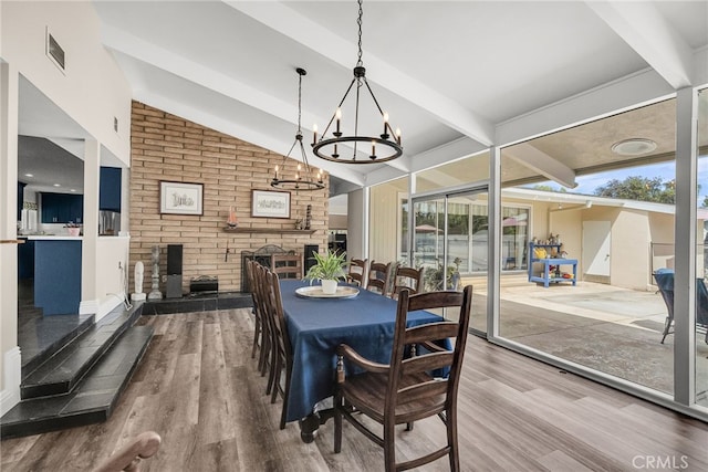 2201 Archdale St, Riverside, CA 92506 - dining area featuring wood finished floors, brick wall, a fireplace, and a chandelier
