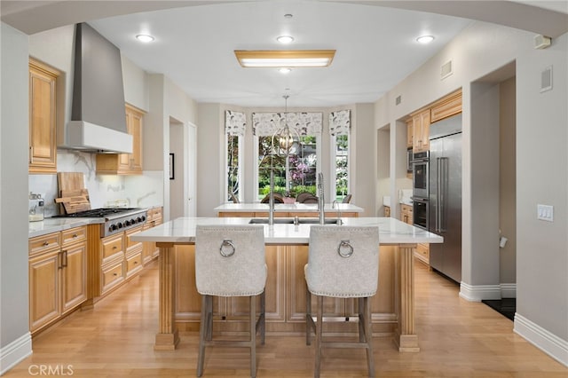 4160 New Hampshire Ave, Claremont, CA 91711 - kitchen featuring wall chimney range hood, a kitchen island with sink, appliances with stainless steel finishes, light wood-style floors, and baseboards