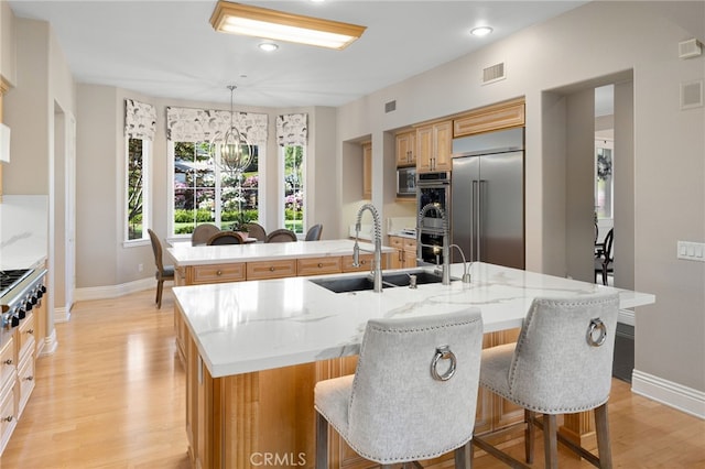 4160 New Hampshire Ave, Claremont, CA 91711 - kitchen with built in appliances, a center island with sink, baseboards, light wood-style flooring, and a sink