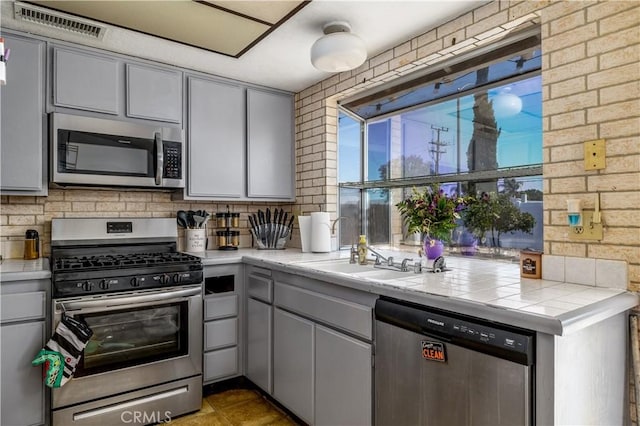 23621 Suncrest Ave, Moreno Valley, CA 92553 - kitchen with stainless steel appliances, gray cabinetry, tile counters, and backsplash